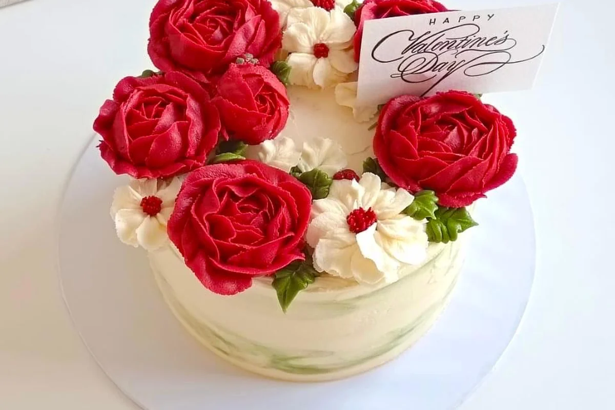 A Valentine's cake with deep red buttercream roses and a Happy Valentine's Day card